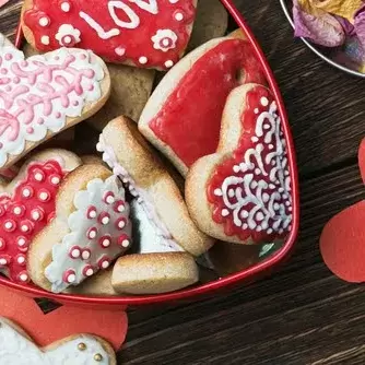 a heart-shaped tin containing decorated heart-shaped sugar cookies perfect for Valentine's Day at your apartment.