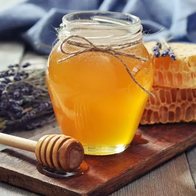 a small jar of honey on a table with several pieces of honeycomb next to it.