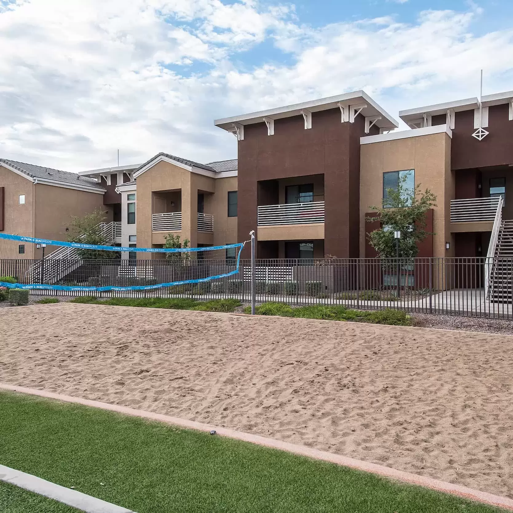 A sand volleyball court in front of apartment buildings.