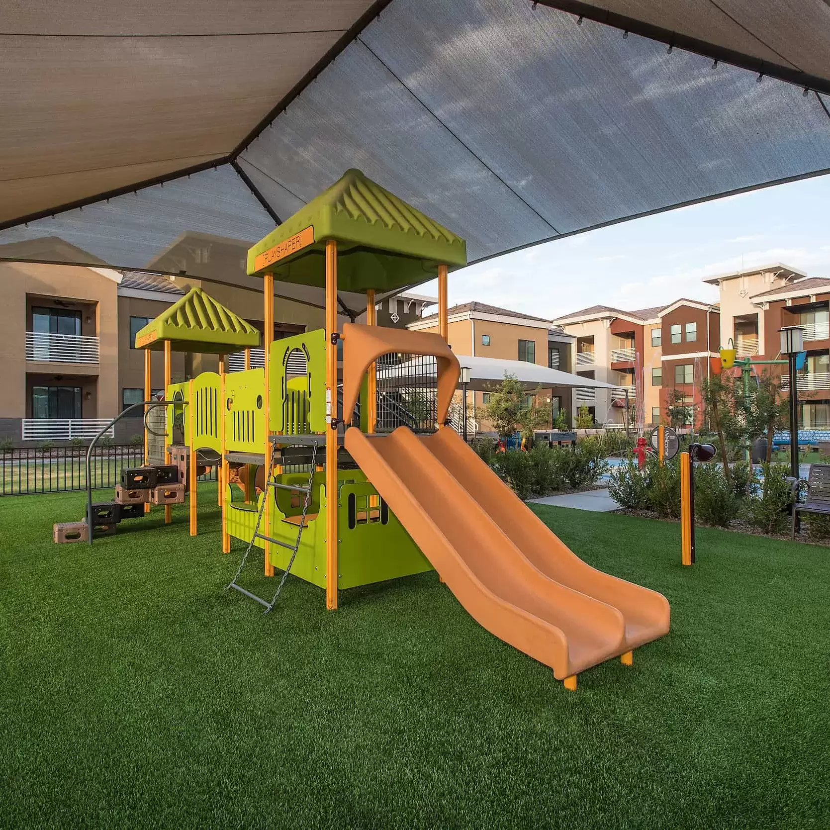 A shaded playground with slides for the children at Liv Northgate.