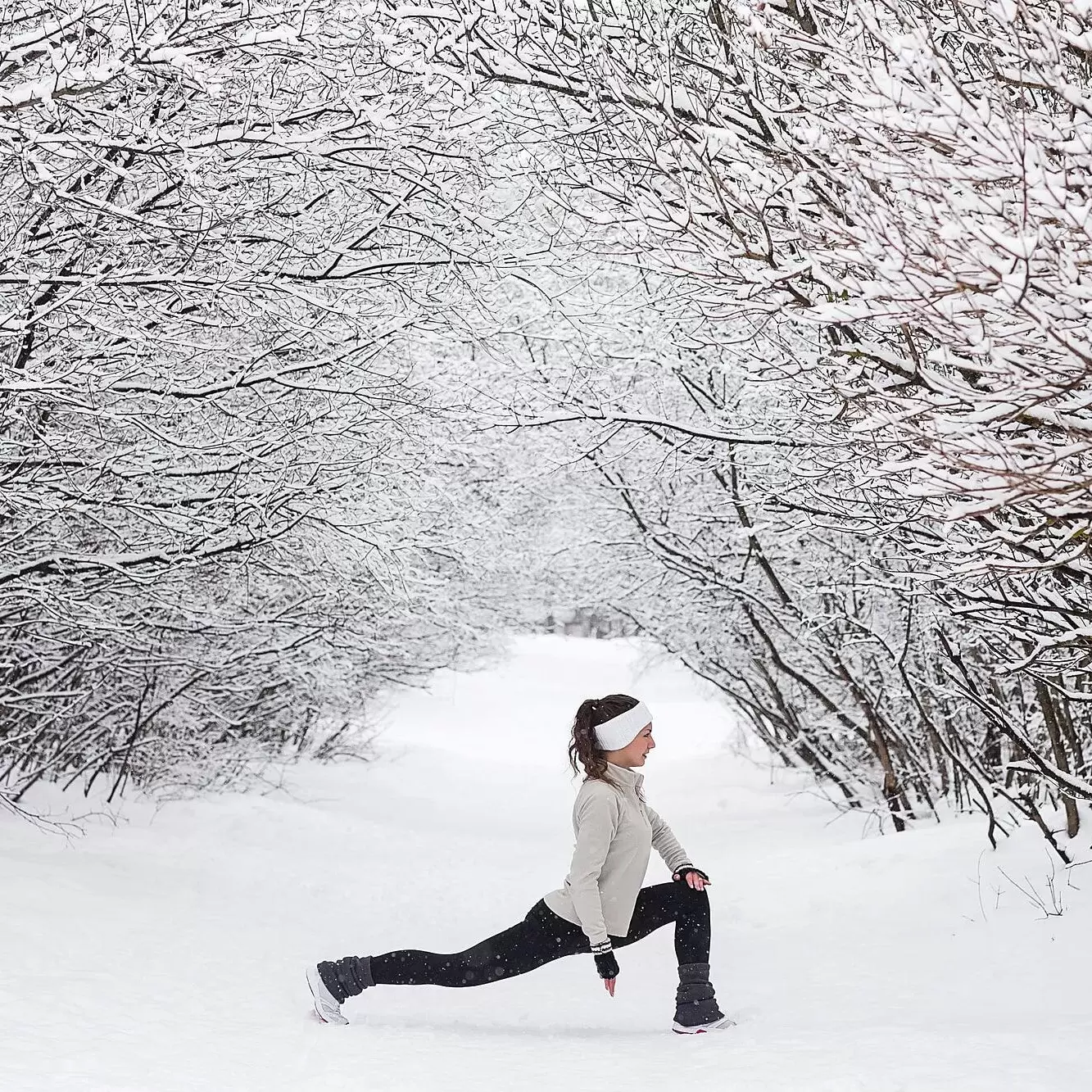 Woman doing lunges in a snowy forest.
