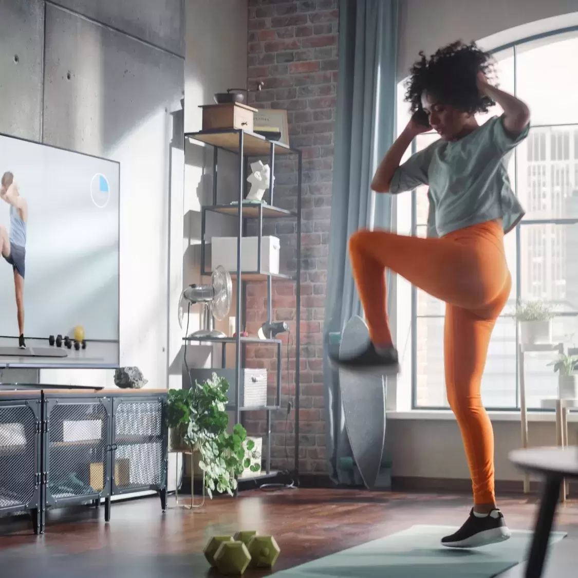 A woman following an aerobic workout on her tv.