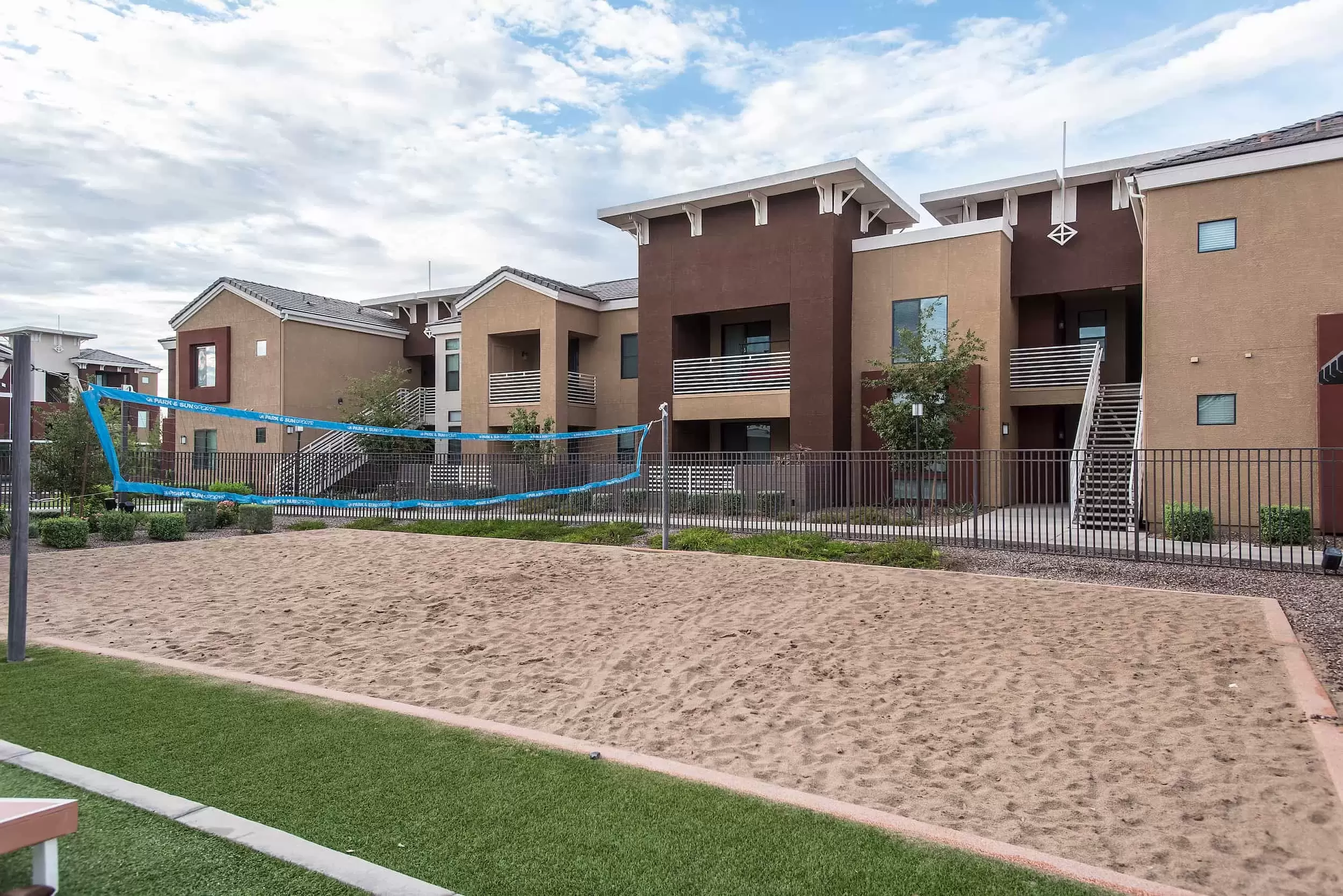 A sand volleyball court in front of apartment buildings.