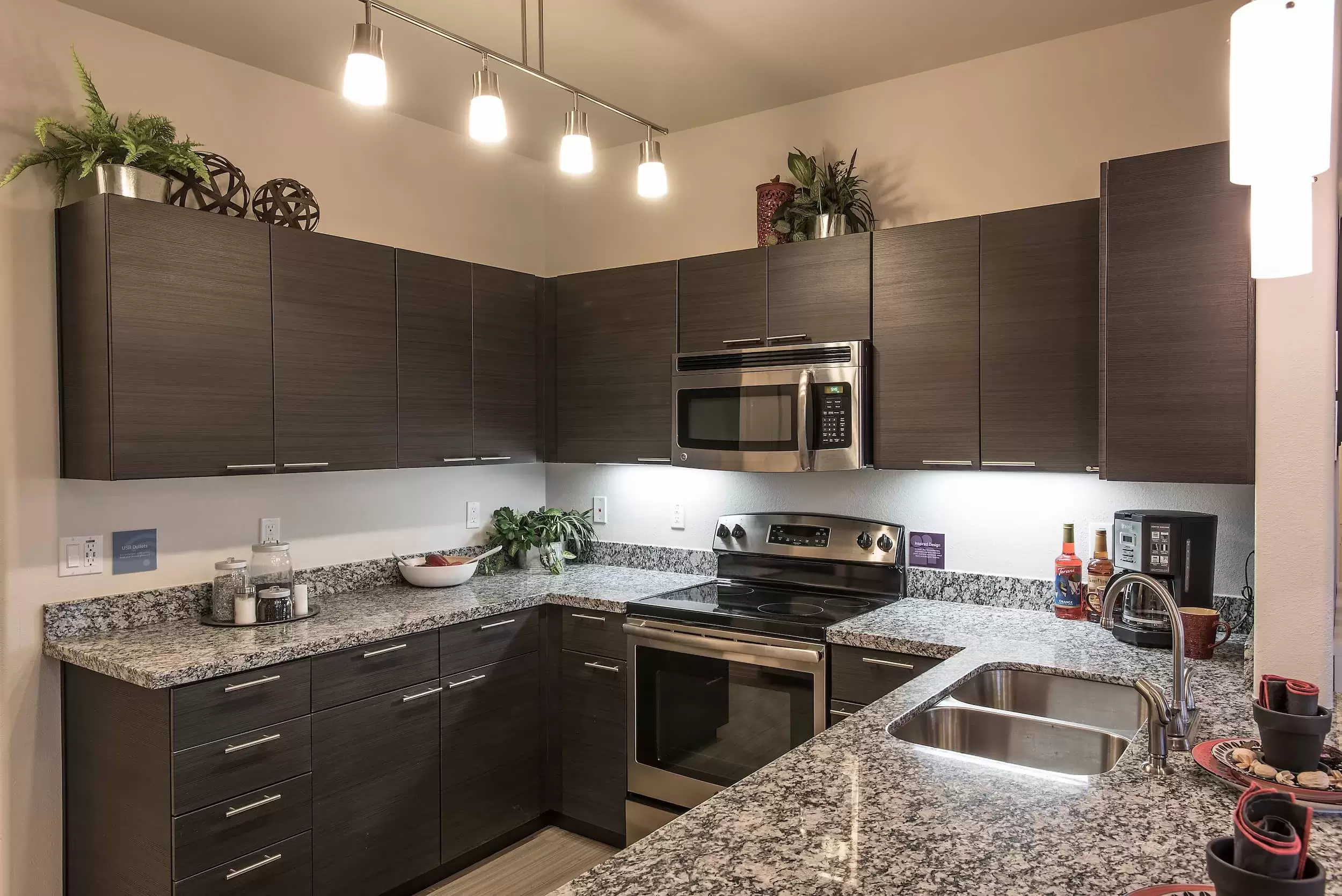 A modern apartment kitchen with stainless appliances and granite countertops.